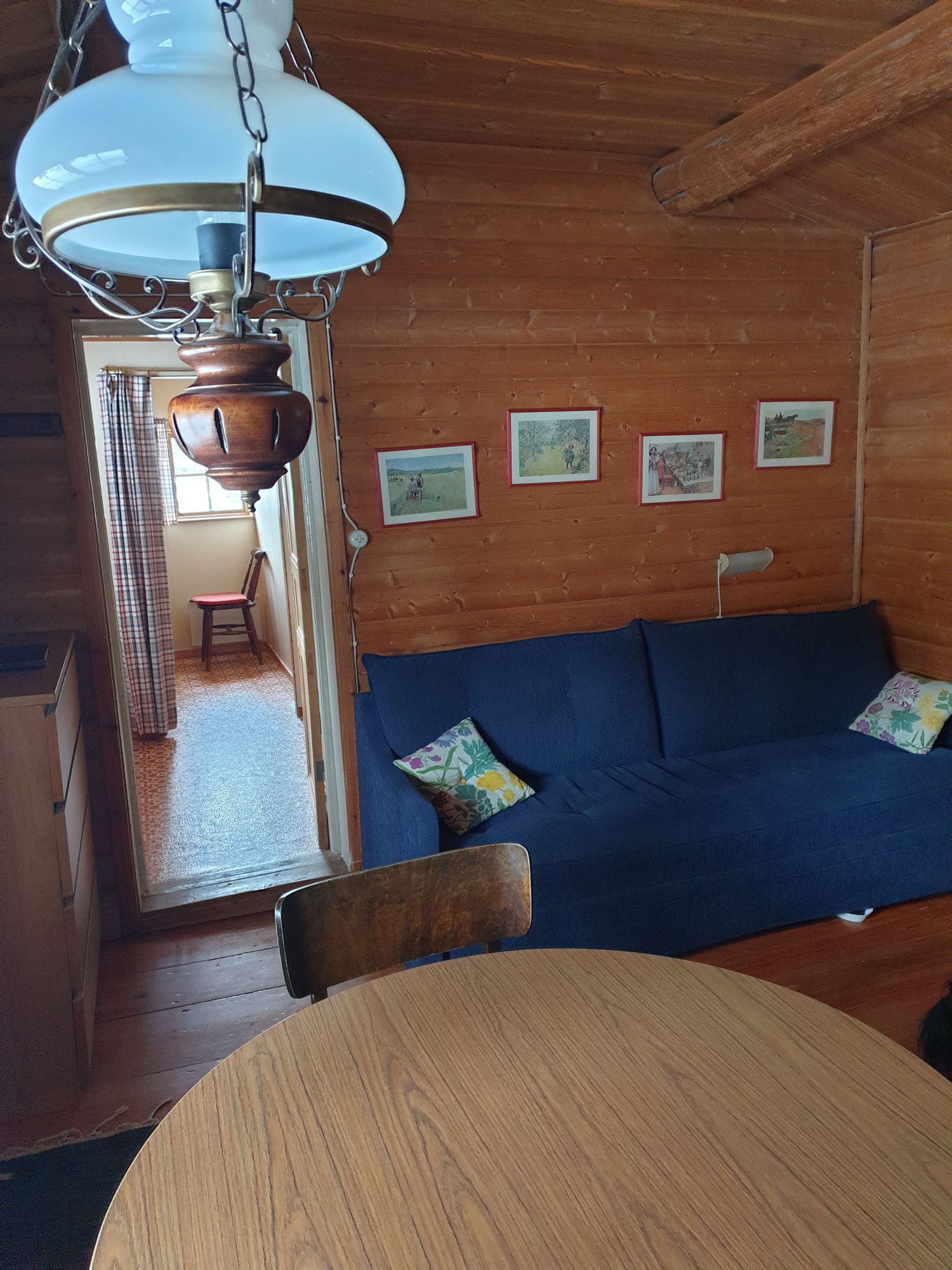 Allrummet i Renhornet med blå bäddsoffa och matbord