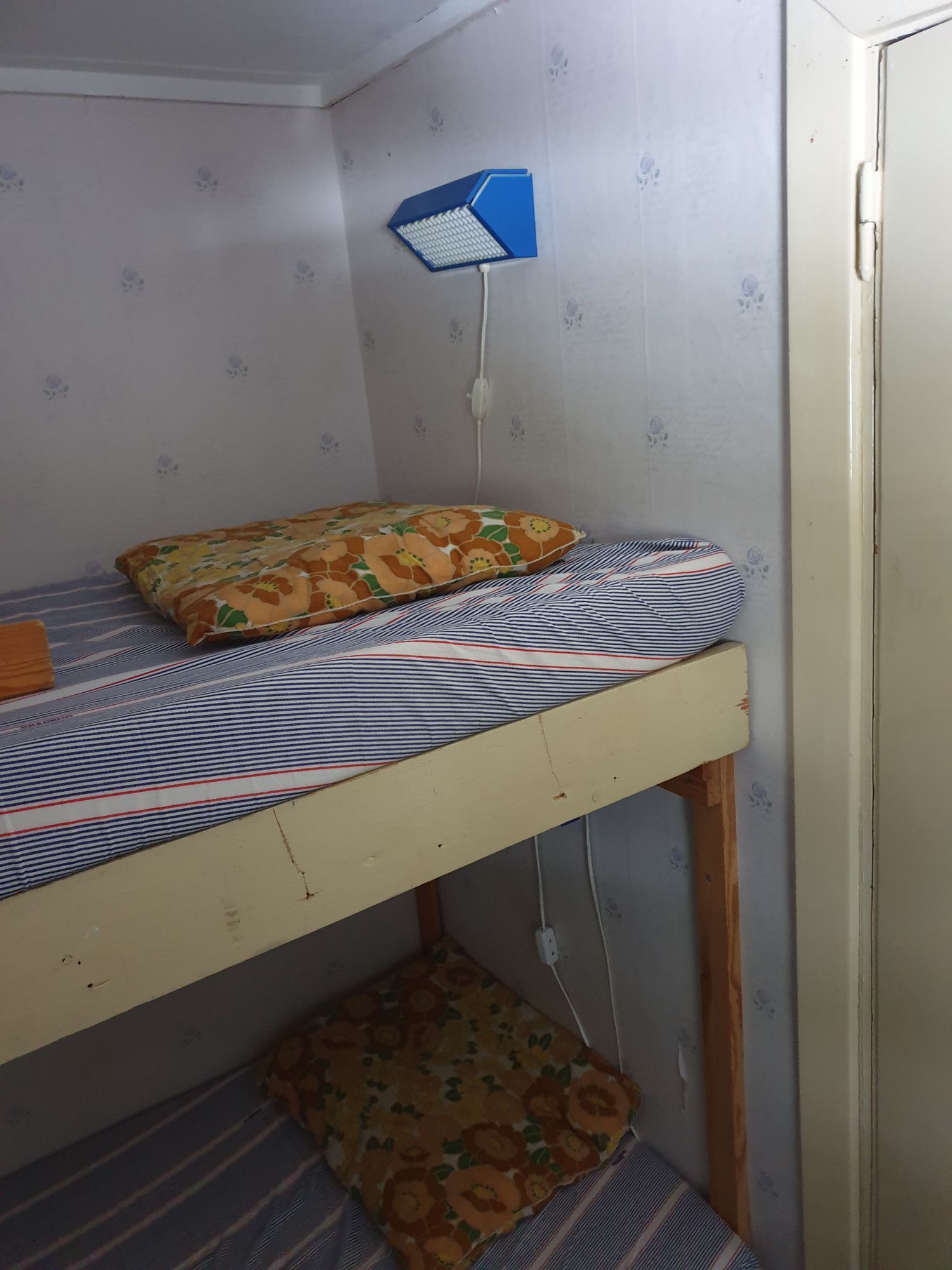 Sovrum i Torpet med säng och vägglampa