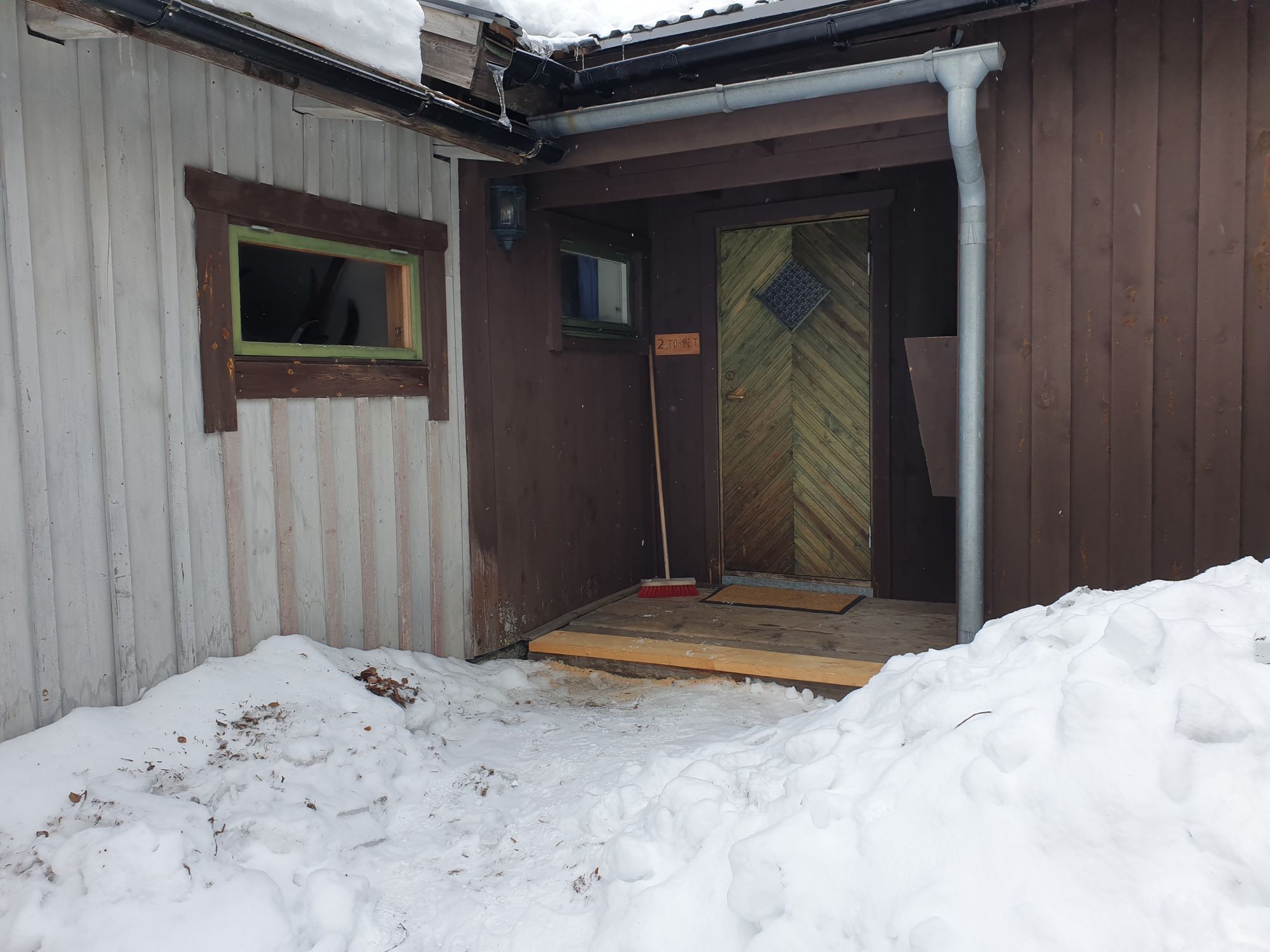 Entrén till Torpet på vintern med snö framför dörren